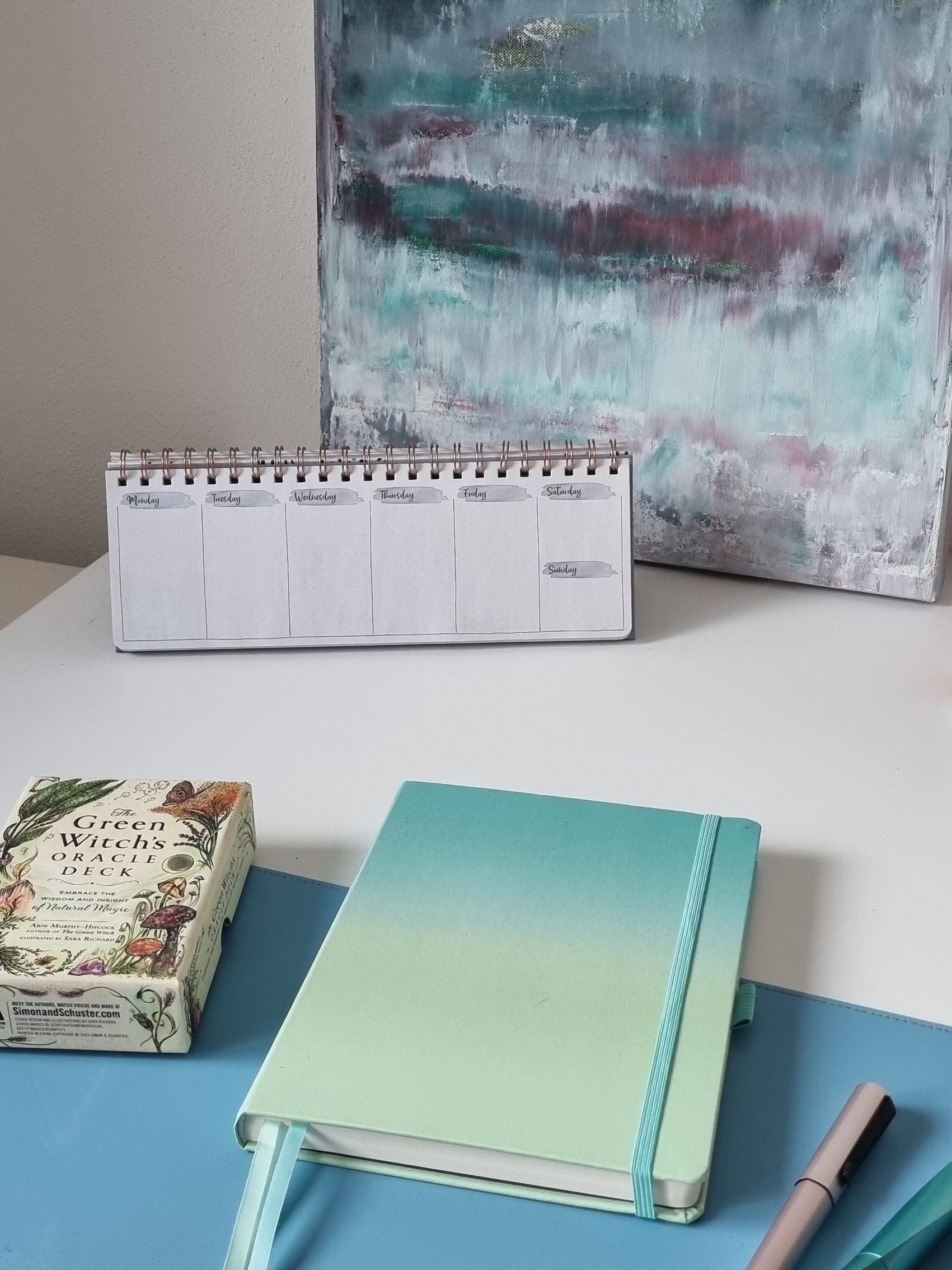 Geschlossenes Notizbuch auf einem Schreibtisch mit Tarotkarten und Füllern